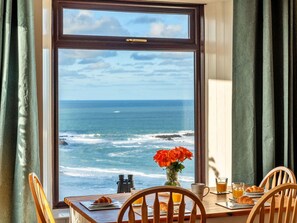 A dining table with breakfast items and a view of the ocean through a window.