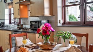 A dining area with a wooden table set for breakfast, including croissants, a vase with flowers, and a bowl. - Beautiful  villa for 2 people with WIFI (Leedstown)