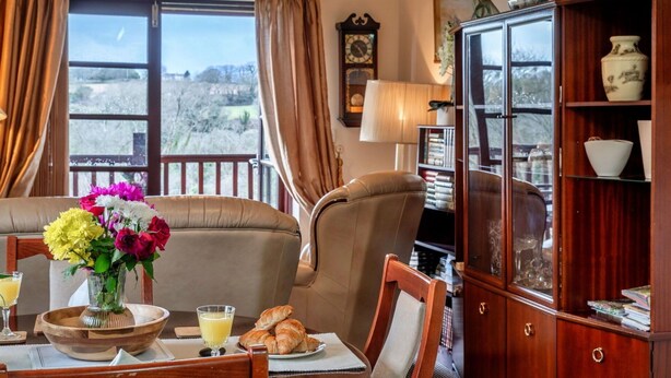 A dining area with a view of the outdoors, a wooden cabinet with glass doors, and a table set with flowers and breakfast items. - Beautiful  villa for 2 people with WIFI (Leedstown)