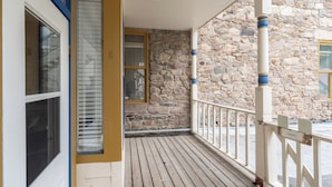Una terraza de madera con un muro de piedra y barandilla blanca.