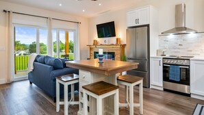 A modern kitchen with a central island, a built-in oven, and a stainless steel refrigerator. - Canandaigua | CMAC | Fire Pit | Hot Tub | Sauna (Canandaigua)
