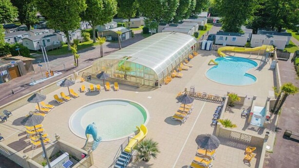 A pool area with multiple swimming pools, sun loungers, and umbrellas.