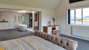 A bedroom with a large bed, a vanity, a mirror, a desk, and a window with a view. - Wonderful  villa for 12 guests with WIFI, hot tub, terrace and pets allowed (Burnham-on-sea)