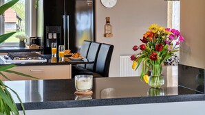A modern kitchen with a black refrigerator, a dining area with a black chair, and a vase of colorful flowers on the counter. - Wonderful  villa for 12 guests with WIFI, hot tub, terrace and pets allowed (Burnham-on-sea)