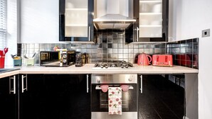 Une cuisine moderne avec des meubles de couleur noire, une cuisinière à gaz, une bouilloire rouge et un grille-pain.