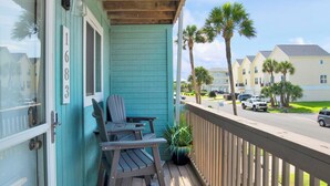 A porch with two Adirondack chairs and a wooden ladder. - Coconut’s Beach House | 2BD/1.5BA | Steps to Beach,  Lake View + Outdoor Shower (Pensacola Beach)