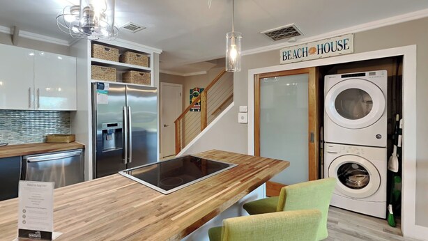 A modern kitchen with a wooden island, stainless steel appliances, and a sign reading "BEACH HOUSE". - Coconut’s Beach House | 2BD/1.5BA | Steps to Beach,  Lake View + Outdoor Shower (Pensacola Beach)