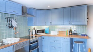 A kitchen with blue cabinets, a microwave, a toaster, and a sink.
