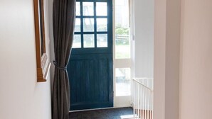 A hallway with a blue door, a hanging light fixture, and a patterned rug.