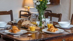 A breakfast table set with croissants, juice, and a vase of flowers. - Stunning  villa for 8 guests with WIFI, TV and pets allowed (Minehead)