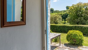 A room with a view of a garden, a wooden bench, and a mirror on the wall. - Stunning  villa for 8 guests with WIFI, TV and pets allowed (Minehead)