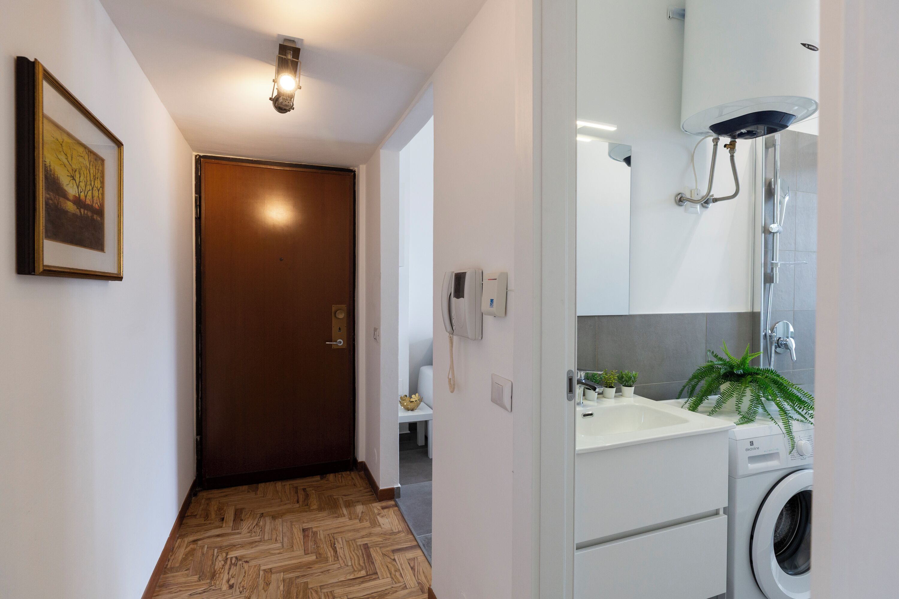 A modern bathroom with a shower, sink, and washing machine.