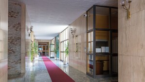 A modern hotel lobby with a red carpet, potted plants, and a glass partition with a wooden frame. - notaMi - Fiordalisi 1 - Flower District (Milan)