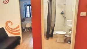 Une salle de bain avec une douche, des toilettes et un rideau.