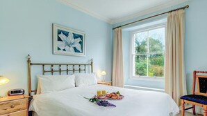 A neatly made bed with a white bedspread, a bedside table with a lamp, a framed picture on the wall, and a window with curtains. - Wonderful  villa for 14 guests with WIFI and pets allowed (Dartmouth)