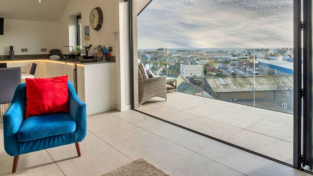 A modern kitchen with a large window, a blue chair, and a view of a town.