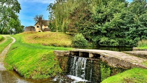 A stone bridge over a small stream with a waterfall, surrounded by lush greenery and a traditional building. - Stunning  villa for 4 people with WIFI, terrace and pets allowed (Minehead)