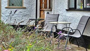 An outdoor seating area with metal chairs and a small table, surrounded by a garden with lavender plants. - Stunning  villa for 4 people with WIFI, terrace and pets allowed (Minehead)
