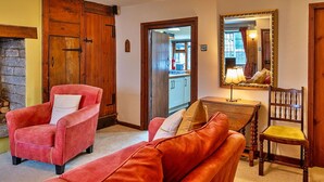 A cozy living room with a red armchair, a wooden table, and a mirror. - Stunning  villa for 4 people with WIFI, terrace and pets allowed (Minehead)