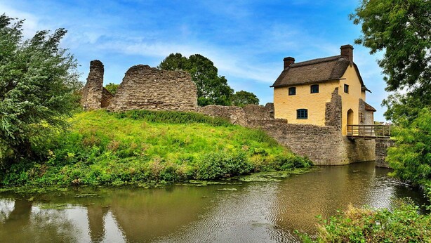 A historic stone structure with a yellow building adjacent to a calm river, surrounded by greenery. - Stunning  villa for 4 people with WIFI, terrace and pets allowed (Minehead)