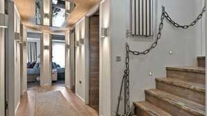 Un interior moderno con una escalera de madera, un pasillo que conduce a un dormitorio y una cadena en la pared.