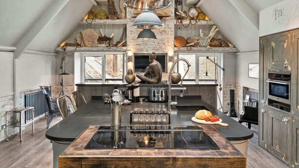 Una cocina amplia con una isla grande, electrodomésticos modernos y decoración rústica.