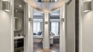 Un pasillo moderno con piso de madera que conduce a un dormitorio con cama, mesita de noche y ventana con cortinas.