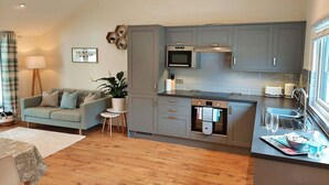 A modern kitchen with grey cabinets, a built-in oven, and a window overlooking the room. - Stunning  villa for 2 guests with hot tub, WIFI (Kingsteignton)