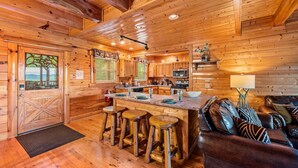 A wooden cabin interior with a kitchen, bar area, and seating.