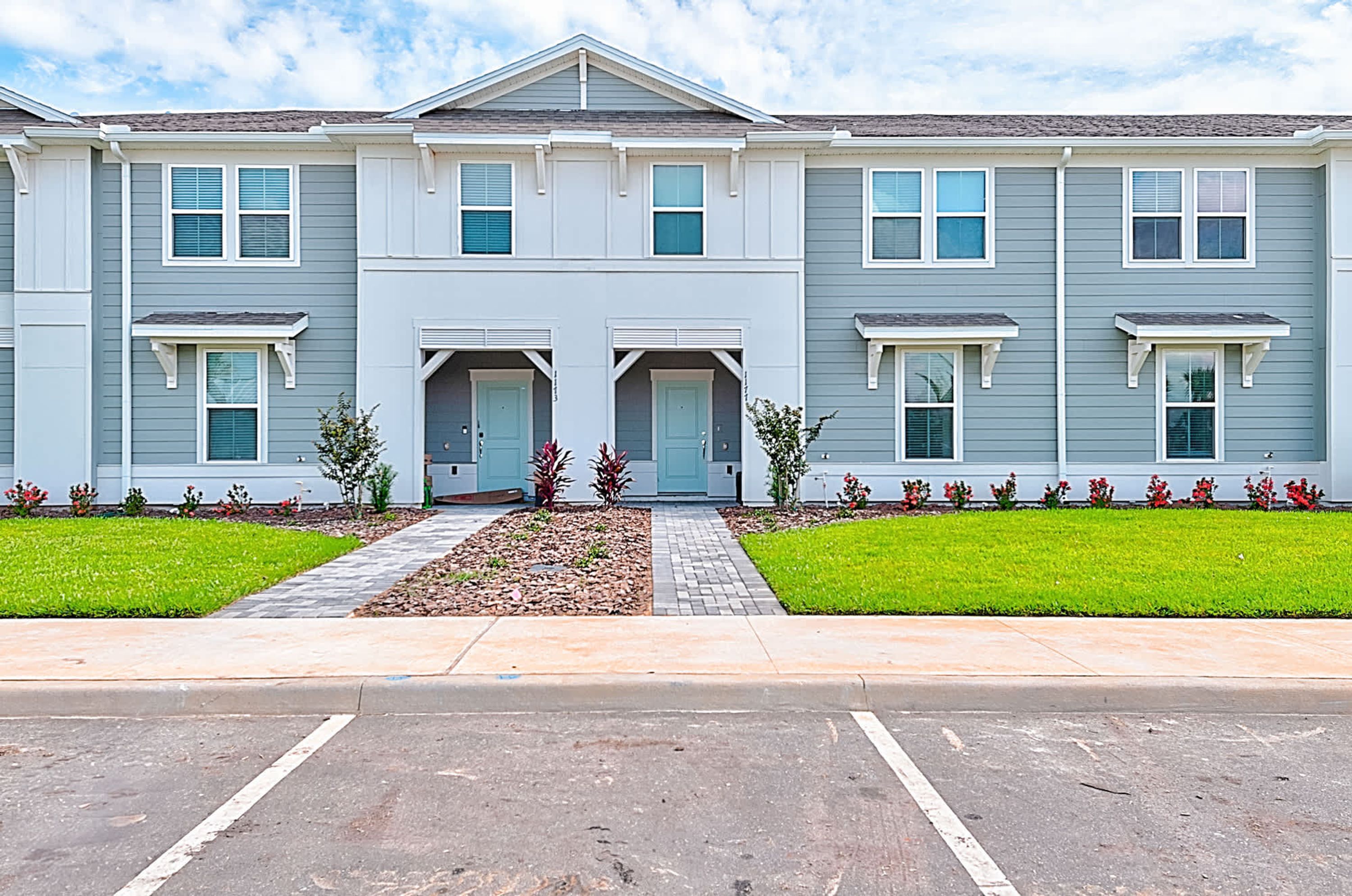 A two-story residential building with a symmetrical facade, central entrance, and a landscaped front yard.