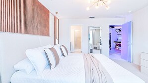 Una camera da letto moderna con un letto grande, un pannello parete a doghe di legno e un lampadario.