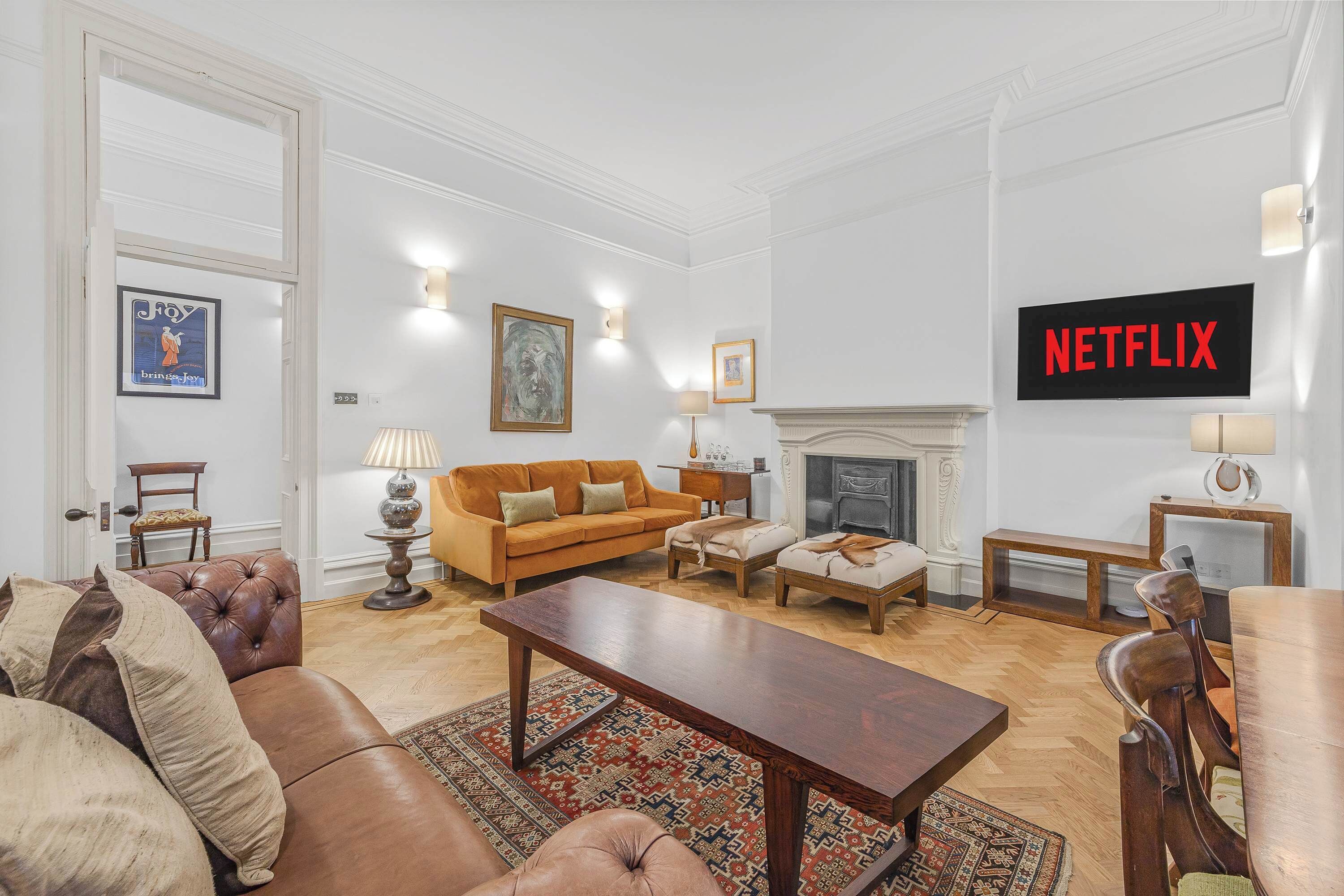 A living room with a fireplace, a sofa, a coffee table, and a television displaying the Netflix logo.