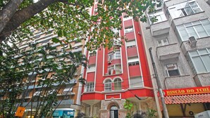 A multi-story building with balconies, a visible storefront, and parked cars. - Conforto e Estilo em Copacabana D056 (Rio de Janeiro)
