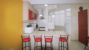 A modern kitchen with a central island, bar stools, and a dining area.