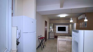 A compact kitchen with a refrigerator, microwave, and dishwasher. There is a small dining area with a chair and a table. - Conforto e Estilo em Copacabana D056 (Rio de Janeiro)
