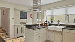 A modern kitchen with a central island, white cabinetry, and a stainless steel range hood.