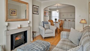 A living room with a fireplace, a dining area, and a kitchen.
