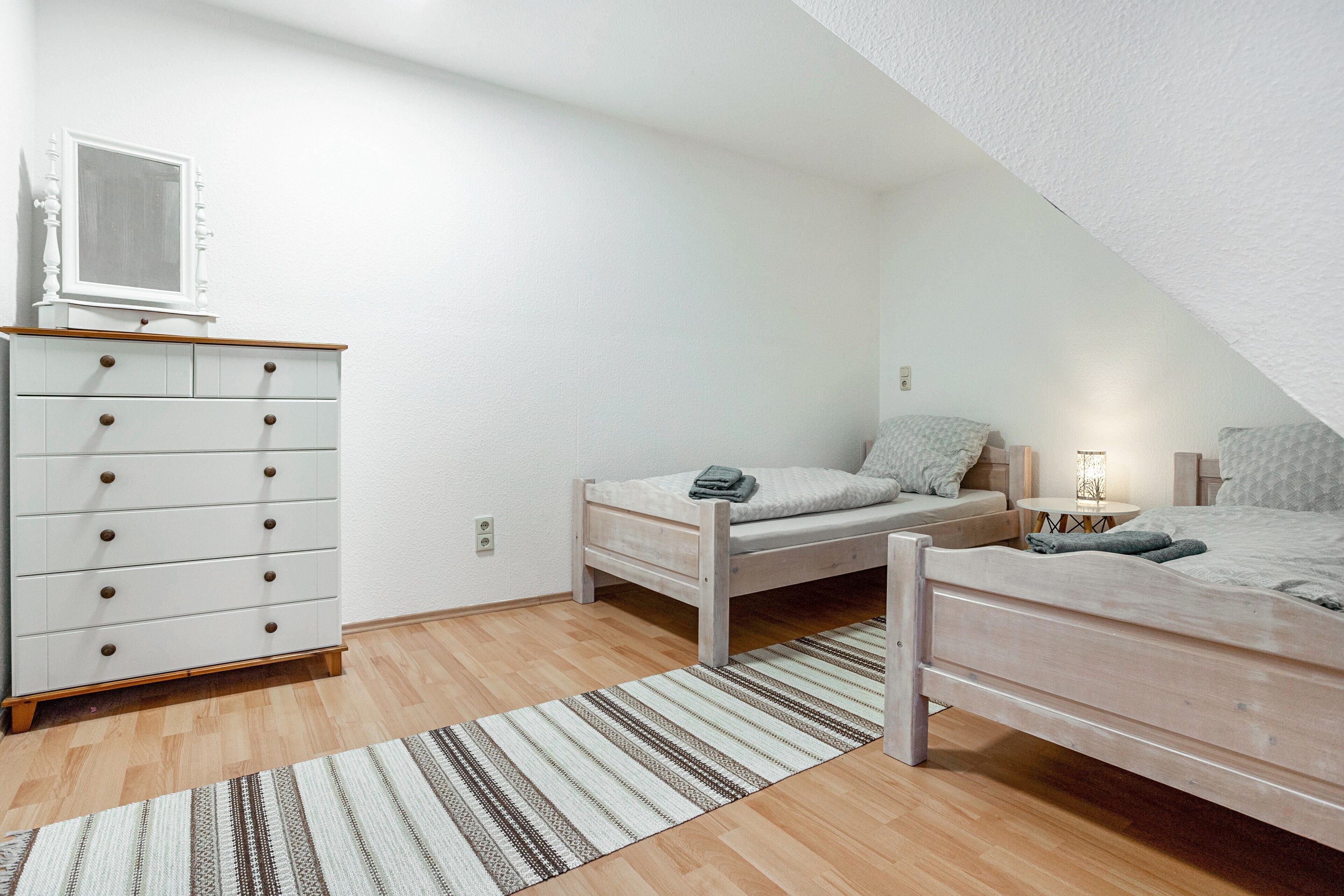 Ein Schlafzimmer mit zwei Einzelbetten, einem Schminktisch, einem Spiegel und einem kleinen Tisch mit einer Lampe.