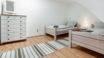 Ein Schlafzimmer mit zwei Einzelbetten, einem Schminktisch, einem Spiegel und einem kleinen Tisch mit einer Lampe.