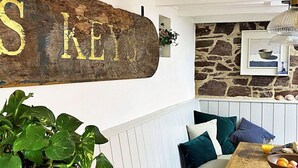 A cozy dining area with a wooden bench, a rustic sign, and a stone wall. - Stunning  villa for 6 people with WIFI and pets allowed (Cawsand)
