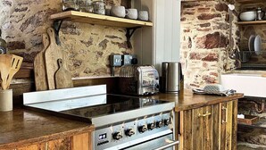 A rustic kitchen with a large stove, wooden shelves, and hanging light fixtures. - Stunning  villa for 6 people with WIFI and pets allowed (Cawsand)