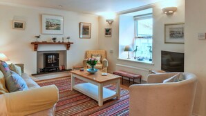 A cozy living room with a fireplace, a sofa, a coffee table, and a window with a view. - Wonderful  villa for 6 people with WIFI, terrace and pets allowed (Cawsand)