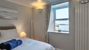 A hotel room with a bed, a window with a view of the sea, a wall-mounted light fixture, and a radiator. - Wonderful  villa for 6 people with WIFI, terrace and pets allowed (Cawsand)