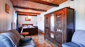 A room with a wooden ceiling, a large wardrobe, a bed with a headboard, and a blue sofa. - Bed and Breakfast 'Breizh' with Private Terrace, Shared Garden and Wi-Fi (CAST)