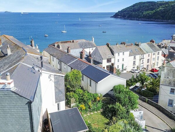 Une ville côtière aux bâtiments traditionnels, offrant une vue dégagée sur la mer et où l’on aperçoit des bateaux au loin.
