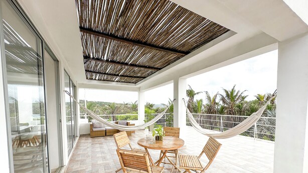 A covered patio with a table and chairs, a hammock, and a view of palm trees. - Apartment for 8 Guests in Sabanilla a Few Steps from the Sea (Sabanilla)