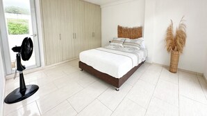 A bedroom with a bed, a fan, a wardrobe, and a decorative plant. - Apartment for 8 Guests in Sabanilla a Few Steps from the Sea (Sabanilla)