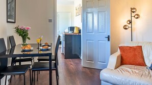 A dining area with a table set for two, a vase of flowers, and a breakfast plate. - Beautiful  villa for 4 people with WIFI and TV (Glastonbury)
