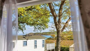 A white mobile home with a large tree in the backyard, a small deck, and a view of a lake. - Wonderful  villa for 6 people with WIFI, pool, TV and terrace (Newtown)