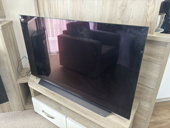 A flat-screen TV on a wooden stand with a drawer below.